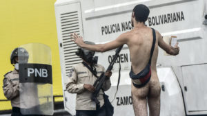 A naked demonstrator remonstrates with riot police during a protest against Venezuelan President Nicolas Maduro, in Caracas on April 20, 2017. Venezuelan riot police fired tear gas Thursday at groups of protesters seeking to oust President Nicolas Maduro, who have vowed new mass marches after a day of deadly unrest. Police in western Caracas broke up scores of opposition protesters trying to join a larger march, though there was no immediate repeat of Wednesday's violent clashes, which left three people dead.
