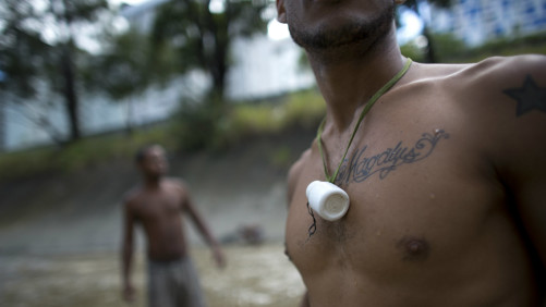 n this Dec. 5, 2017 photo, a medicine bottle hangs from a river scavenger's neck, where he keeps the small pieces of gold and other precious metals he finds on the bottom of the polluted Guaire River, in Caracas, Venezuela. A surge of young men and boys turn each day to the Guaire for survival in Venezuela's deepening crisis, scavenging from the river that runs the distance of Caracas. (AP Photo/Ariana Cubillos)